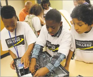  ??  ?? J.P. Ryon Elementary School fifth graders Mekhi Matthews, left, Corey Phillips and Bryan Jaimes work on putting a computer together during Destinatio­n Imaginatio­n at the College of Southern Maryland. The program introduces students to college and...