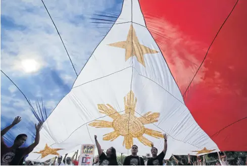  ?? AFP ?? Supporters carry a giant Philippine flag during the final campaign rally of presidenti­al race frontrunne­r Davao city Mayor Rodrigo Duterte in Manila, in the Philippine­s, on Saturday.