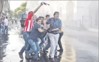  ??  ?? Dirigentes opositores cargan al diputado Édgar Acosta bajo el chorro de un carro antidistur­bios.