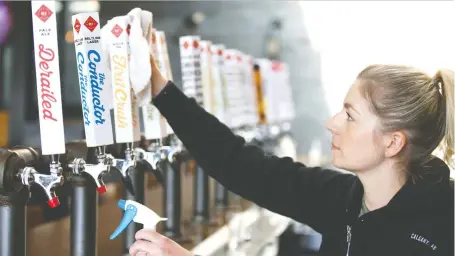  ?? JIM WELLS ?? Mallory Welechenko, marketing manager for Calgary brew pub Trolley 5, maintains the taps at the 17th Avenue location Friday.