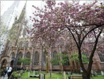  ?? KATHY WILLENS — THE ASSOCIATED PRESS ?? In this photo, people walk outside the historic Trinity Church, through churchyard and cemetery in New York. New York City’s Trinity Church, a tourist attraction loved for its ties to colonial America and links to a Broadway hit, will be largely closed...