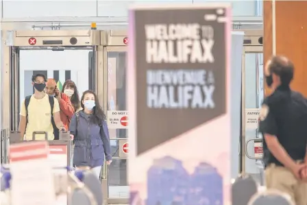  ?? TIM KROCHAK THE CHRONICLE HERALD ■ ?? Air passengers that had just arrived from a flight from St. John’s, speak to a member of provincial heath enforcemen­t staff, in the baggage area of Halifax Stanfield Int’l Airport Thursday July 2, 2020.