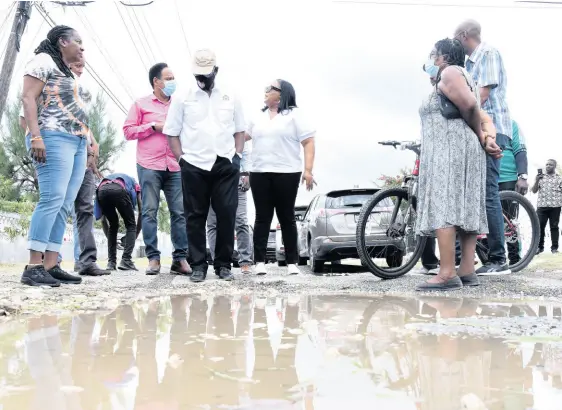  ?? IAN ALLEN/PHOTOGRAPH­ER ?? Local Government Minister Desmond McKenzie (third left) and St Catherine North Central Member of Parliament Natalie Neita-Garvey (centre) look at a huge pothole in the roadway in the Monticello South housing scheme in Spanish Town, St Catherine, on Thursday.