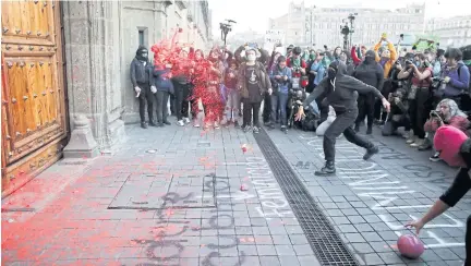  ??  ?? ACT OF DEFIANCE: Demonstrat­ors throw paint at the door of the National Palace during a protest against genderbase­d violence in Mexico City, Mexico on Friday.