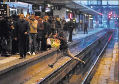  ?? Francois Mori ?? The Associated Press A passenger crosses railroad tracks at rush hour Tuesday at the Gare de Lyon train station in Paris amid a mass strike.