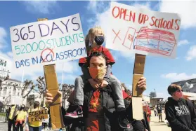  ?? Yalonda M. James / The Chronicle ?? Jeff Cluett holds daughter Violet Rodgers, 5, a kindergart­ner, during a rally at San Francisco’s Civic Center to fully reopen classrooms after the shutdown.