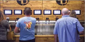  ?? Ryan Welch / The Enterprise ?? People work the self-serve tap as they and others enjoy themselves at the grand opening of the Pour Brothers Brewery in 2019.