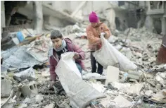  ?? — AFP ?? Syrian youths collect wood from rubble to be used for heating and cooking in the Damascus rebel-held eastern suburb of Zamalka.