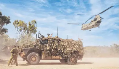  ?? ACTION STATIONS: Soldiers take cover behind a Bushmaster Protected Mobility Vehicle as a CH- 47 Chinook lifts off at Shoalwater Bay Training Area in Central Queensland during Exercise Hamel 2018. Picture: LSIS JAKE BADIOR ??