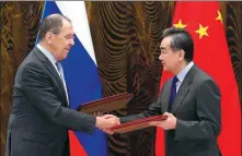  ?? AFP ?? Russian Foreign Minister Sergey Lavrov and China’s State Councilor and Foreign Minister Wang Yi exchange documents after their talks in Guilin, Guangxi Zhuang autonomous region, on Tuesday.