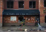  ?? (AP/Detroit News/Andy Morrison) ?? Detroit firefighte­rs clean up in front of Traffic Jam and Snug Restaurant on Friday after an overnight fire.