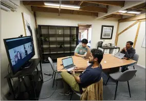  ?? AP PHOTO/ERIC RISBERG ?? Runx CEO Ankur Dahiya, center, takes part in a video meeting with employees JD Palomino, top left, and Nitin Aggarwal, right, at a rented office in San Francisco, Friday, Aug. 27, 2021. Technology companies like Runx that led the charge into remote work early as the pandemic unfurled, are confrontin­g a new challenge as it winds down: how, when and even whether they should bring their long-isolated employees back to offices that have been designed for teamwork.