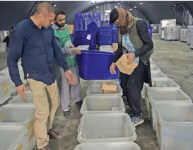  ?? (AFP) ?? Independen­t Election Commission employees load biometric devices in boxes, in Kabul on Wednesday