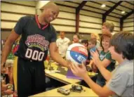  ??  ?? Harlem Wizard Dwayne “Swoop” Simpson signs a basketball for Derrek Mann Friday night at Penn Valley Church in Telford.