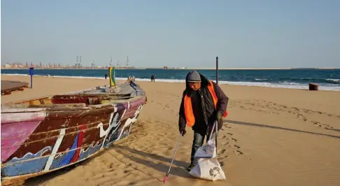  ??  ?? 一位环卫工人在秦皇岛­市海港区金梦海湾沙滩­上捡拾垃圾