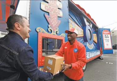  ?? Elaine Thompson / Associated Press ?? Amazon worker Khayyam Kain hands a package to a customer at an Amazon Treasure Truck in Seattle. The Treasure Truck is a quirky way for the online retailer to connect with shoppers in person.