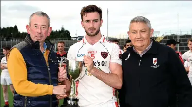  ??  ?? Frank Doran Safeguard Security sponsors (left) and Tim Ryan Chairman East Kerry Board presenting the East Kerry Super League Division 1 cup to winning Rathmore Captain Brendan O’Keeffe after his side defeated Fossa in the final