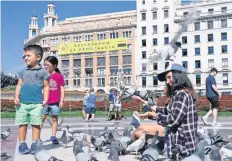  ??  ?? Una mujer alimenta palomas en la plaza Cataluña de Barcelona. En el edificio del fondo, una pancarta que dice: “Sí. Referéndum es democracia”.