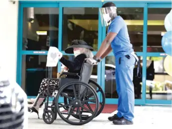  ?? WILFREDO LEE/AP PHOTO ?? A worker at a Miami nursing home wheels a resident back inside after a drive-by visit from the resident’s friend. Congress must provide more funding to help nursing homes stay safe from COVID-19, AARP Illinois writes.