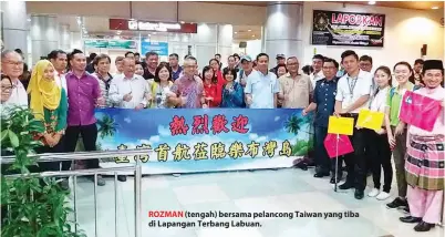  ??  ?? ROZMAN (tengah) bersama pelancong Taiwan yang tiba di Lapangan Terbang Labuan.