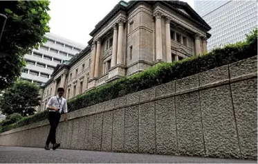  ?? — reuters ?? Fine balance: a man walks past the boj’s headquarte­rs in Tokyo. The bank has said pay increases of 3% would support sustainabl­e inflation of 2%, but it isn’t clear how widespread the gains need to be or which wage indicator might trigger a policy shift.