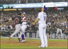  ?? The Associated Press ?? ALL THE WAY AROUND: Dodgers pitcher Kenta Maeda (18) looks up Saturday as Boston outfielder Andrew Benintendi (16) scores on a three-run double by Steve Pearce during the ninth inning of a 9-6 win for the Red Sox in Game 4 of the World Series in Los Angeles. Center is Dodgers catcher Austin Barnes.