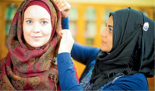  ?? PHOTOS: ROBERT KITCHIN/FAIRFAX NZ ?? Jannat Khan, right, gives Fairfax NZ reporter Rachel Thomas a lesson on tying a hijab - the traditiona­l head covering worn by Muslim women.