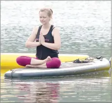  ?? Keith Bryant/The Weekly Vista ?? Holly Parlier, who owns property in Bella Vista, sits on a paddleboar­d during a guided meditation session at the Lake Avalon Beach.