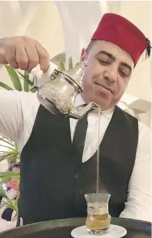  ??  ?? Rashid, a fez-topped waiter, pours sweet mint tea after dinner at Rick’s Café in Casablanca, Morocco.