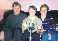  ?? ?? Danny Keane from Fermoy, displaying his Irish dancing championsh­ip cup and medal won in 2000, pictured with his parents Donal and Della, when TheAvondhu visited him 21 years ago.