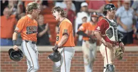  ?? IAN MAULE/TULSA WORLD ?? Arkansas catcher Michael Turner (12) looks onward as Oklahoma State infielder Aidan Meola (2) and utility Nolan McLean (13) yell after McLean's two-run home run in the top of the 10th inning Sunday night in Stillwater.