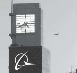  ?? TED S. WARREN AP ?? An airplane flies past the Boeing logo on the company's headquarte­rs in Chicago.