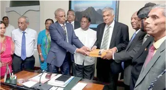  ??  ?? A report on constituti­onal reforms proposals being handed over to Prime Minister Ranil Wickremesi­nghe by the public representa­tion committee