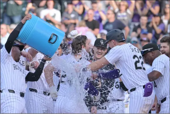  ?? HYOUNG CHANG — THE DENVER POST ?? Teammates celebrate with Colorado Rockies third baseman Ryan Mcmahon after his walk-off grand slam to beat the Tampa Bay Rays at Coors Field on Friday. The Rockies won 10-7.