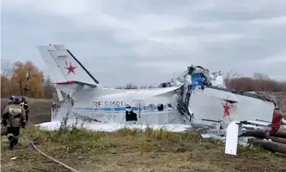  ?? Photograph: TASS ?? Rescue workers inspect the L-410 light aircraft after it crashed in Tatarstan.