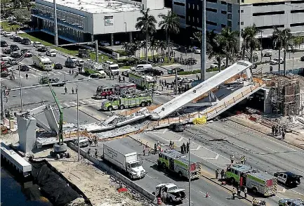  ?? PHOTO: AP ?? Emergency personnel respond after a new pedestrian bridge collapsed on to a highway in Miami, crushing several vehicles and killing at least four people.