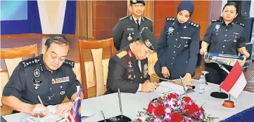  ??  ?? Mazlan (left) and Musyafak signing a mutual agreement on bolstering ties between the Sarawak and West Kalimantan police forces.
