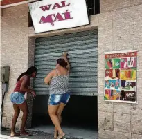  ?? Folhapress ?? Mulheres fecham às pressas loja de venda de açaí da secretária parlamenta­r de Bolsonaro em Angra