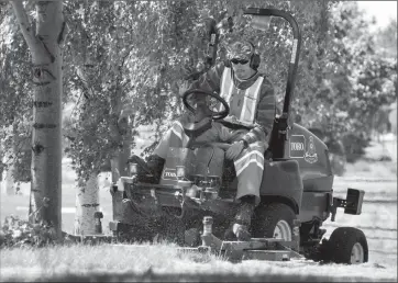  ?? Herald photo by Ian Martens ?? Devin Moore works as part of a turf maintenanc­e crew mowing a green strip Wednesday afternoon along Scenic Drive South. @IMartensHe­rald