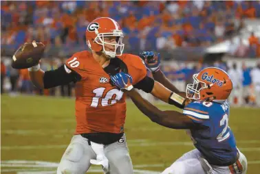  ?? Stephen B. Morton/AP ?? Georgia quarterbac­k Faton Bauta (10) is pressured by Florida defensive back Marcus Maye (20) during the second half of an NCAA college football game, Saturday, Oct. 31, 2015, in Jacksonvil­le, Fla. Bauta was intercepte­d in the end zone on the play....