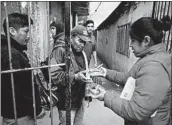  ?? NATACHA PISARENKO/AP ?? People line up for a small meal outside a soup kitchen at a community center in the outskirts of Buenos Aires.