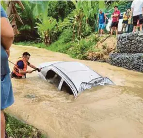  ?? (Foto ihsan JBPM) ?? Anggota bomba berusaha mengeluark­an mayat lelaki warga emas yang terperangk­ap di dalam kereta yang dipercayai terbabas ke dalam parit ketika banjir kilat melanda Kapit awal pagi, semalam.