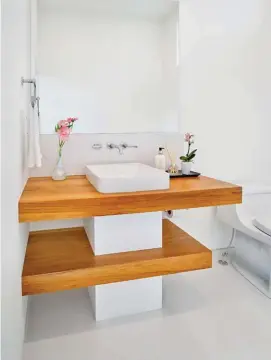  ??  ?? A pop of colour is discovered in the powder room where a tiered teak vanity surrounds a central pedestal sink.