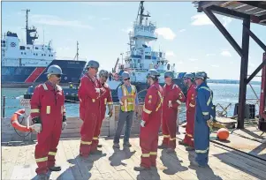  ?? GREG MCNEIL/CAPE BRETON POST ?? Mike Moore, centre in yellow vest, is the region manager for commercial interests for Heddle Marine. He’s shown giving instructio­n to some of the company’s workforce prior to the start of demobilizi­ng a barge at Sydport.