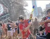  ?? ERIN HOOLEY/CHICAGO TRIBUNE ?? People spray festivalgo­ers with water during Herobust’s set on a hot final day of Lollapaloo­za in 2018.