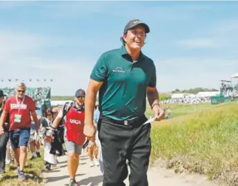  ?? Julio Cortez, The Associated Press ?? Phil Mickelson walks off the course smiling with his scorecard in hand after finishing the 18th hole Saturday during the third round of the U.S. Open.