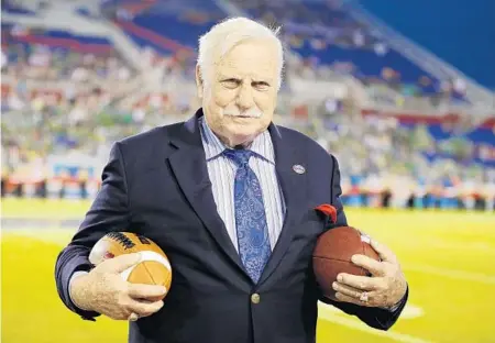  ?? JOEL AUERBACH/AP ?? Former Florida Atlantic and Miami head coach Howard Schnellenb­erger holds the game balls prior to the start of the Boca Raton Bowl game between Marshall and Northern Illinois in 2014 at FAU Stadium. Schnellenb­erger died Saturday at age 87.