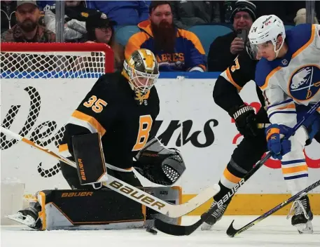  ?? Getty imageS pHOtOS ?? ‘VERY SPECIAL’: Bruins goalie Linus Ullmark makes a save against Buffalo’s Dylan Cozens during the first period at KeyBank Center on Friday night in Buffalo, N.Y. Below, Brad Marchand skates up ice as Colin Miller defends.