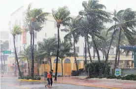  ?? AFP ?? La gente camina por la calle mientras los vientos y la lluvia golpean Miami.