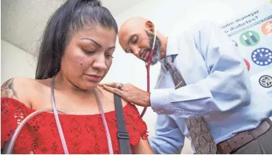  ?? TOM TINGLE/THE REPUBLIC ?? Dr. Maurice Lee checks patient Yoana Nava Lugo in the St. Vincent de Paul medical clinic in Phoenix.
